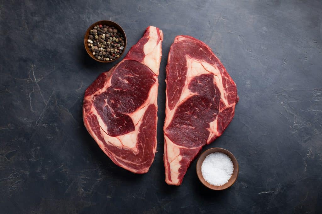 Raw fresh marbled meat Steak Ribeye Black Angus on black marble background.